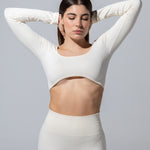 Model wearing The Seamless Long Sleeve Top in cream with cream leggings, hands behind head