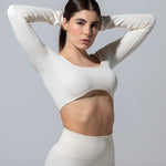 Model in The Seamless Long Sleeve Top in cream, cropped hem and scoop neck, three-quarter view