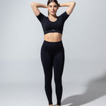 Model wearing The Seamless Crop Top in black with black leggings, full-length front view
