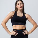 Model wearing The Seamless Bra Top in black with matching black leggings, front view