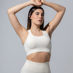 Model in The Seamless Bra Top in cream, arms raised overhead, front view
