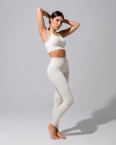Model wearing The Seamless Legging in cream with a cream bra top, full-length three-quarter view